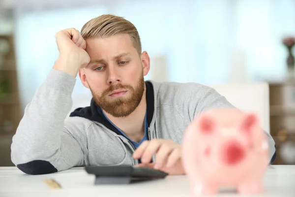 Hombre Serio Con Alcancía Haciendo Cálculos —  Fotos de Stock