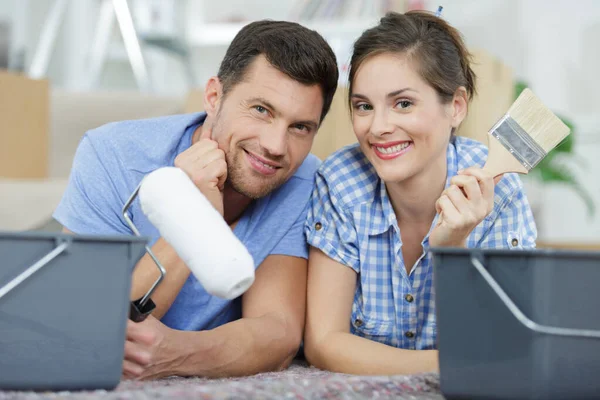 Feliz Casal Sorrindo Deitado Chão Com Escovas — Fotografia de Stock