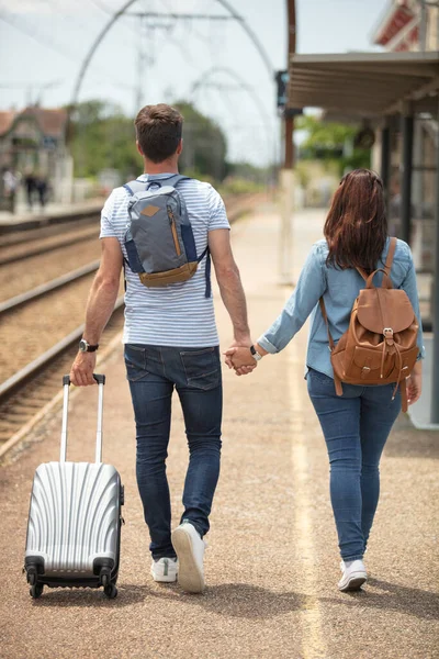 スーツケースを引っ張って電車のホームを歩くカップル — ストック写真