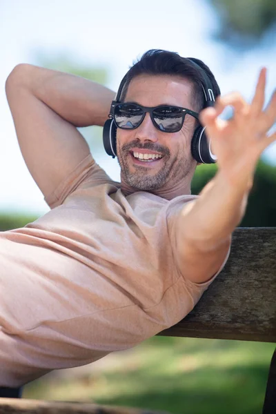 Hombre Con Auriculares Parque Haciendo Buen Gesto —  Fotos de Stock