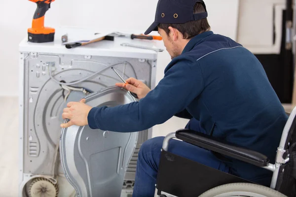Tekerlekli Sandalyedeki Tamirci Çamaşır Makinesini Tamir Ediyor — Stok fotoğraf