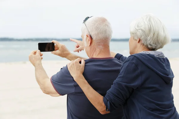 高齢のカップルは携帯電話で旅をし — ストック写真