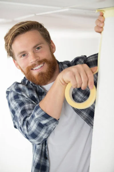 Hombre Sonriente Aplicando Cinta Adhesiva Mientras Redecora —  Fotos de Stock