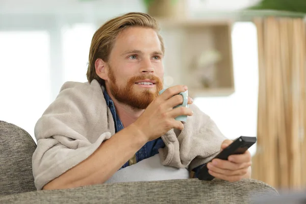 Genç Adam Çay Içiyor Kanepede Televizyon Seyrediyor — Stok fotoğraf