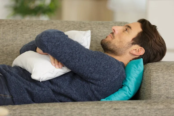 Uomo Sdraiato Sul Divano Abbracciando Cuscino — Foto Stock