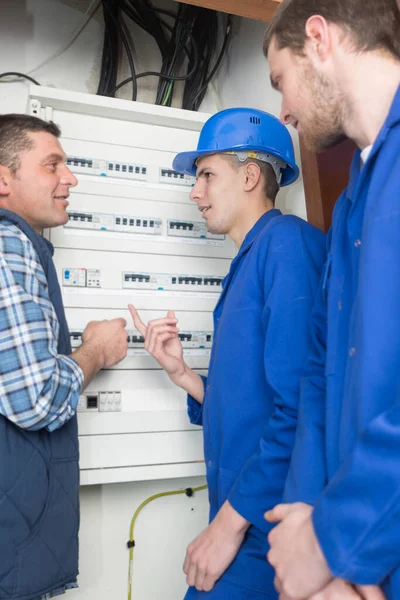 tradesmen and apprentice installing a distribution board