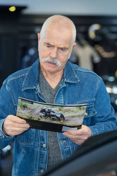 Homem Idoso Leitura Brochura Quad Dealer — Fotografia de Stock