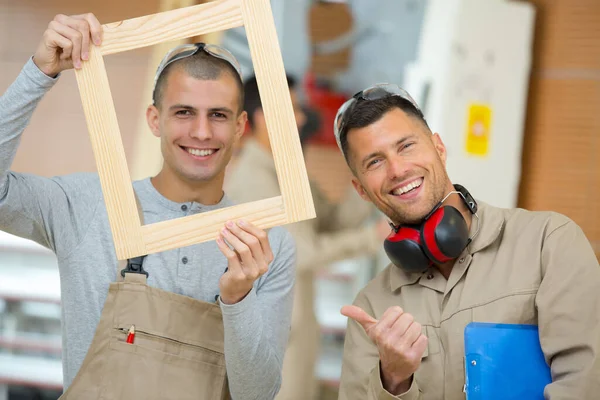 Male Workers Smiling Holding Wooden Picture Frame — Stock Photo, Image