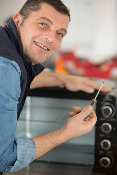 Man Som Håller Skruvmejsel Bredvid Elektrisk Ugn — Stockfoto