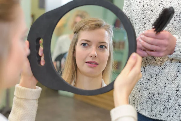 若い女性が鏡の中で髪をチェックし — ストック写真