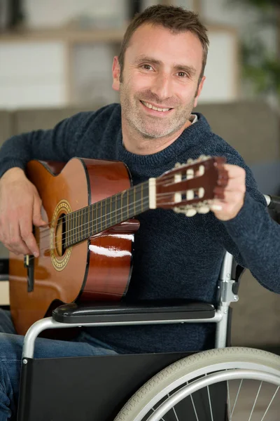 Sorrindo Homem Uma Cadeira Rodas Afinando Sua Guitarra — Fotografia de Stock
