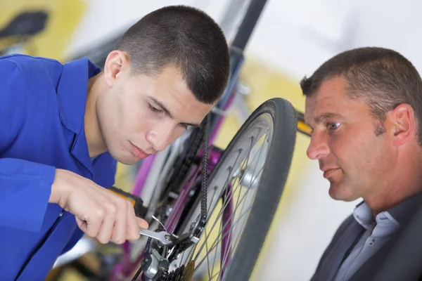 自転車整備士と研修生がワークショップで自転車を修理し — ストック写真