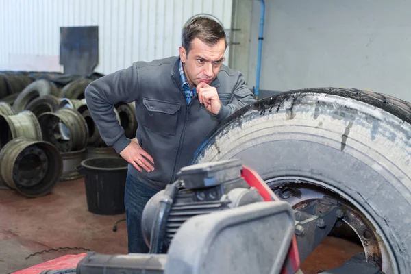 Mechanic Looking Pensively Large Tyre — Stock Photo, Image