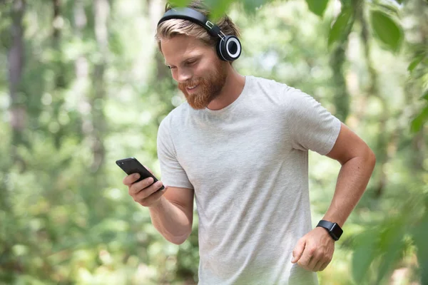 Sprawny Młodzieniec Ćwiczący Lesie Słuchając Muzyki — Zdjęcie stockowe