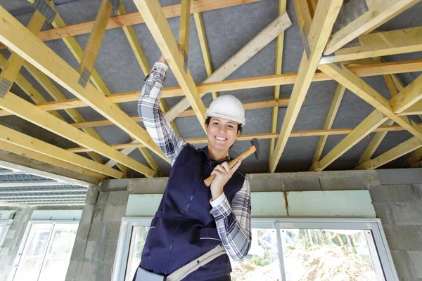 屋根の上で働くハンマーを持つ女性建設労働者 — ストック写真