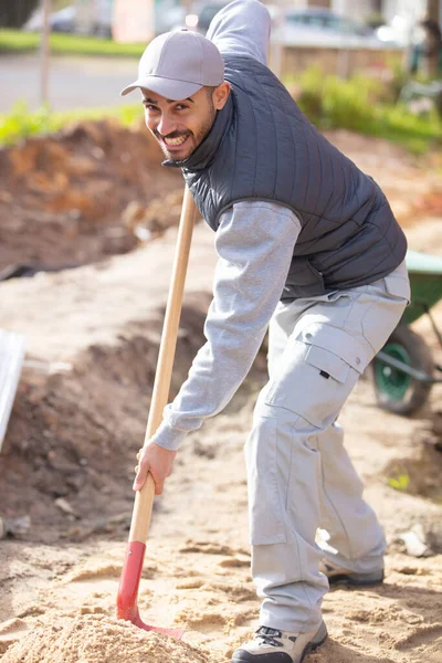 シャベルを持って建設現場で頑張ってる男 — ストック写真