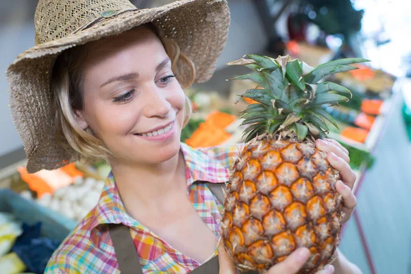 藁帽子をかぶってパイナップルを持っている女性 — ストック写真