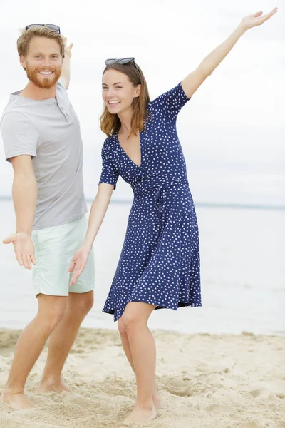 腕の中に立っているかわいいカップルがビーチでワイド オープンします — ストック写真