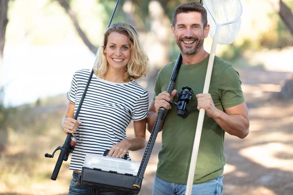 魚棒と網で釣りに行くカップルは — ストック写真