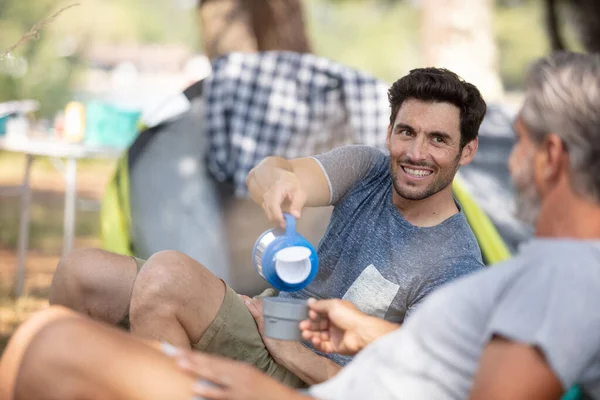 フラスコから熱い飲み物を注ぐキャンプ旅行中の男性 — ストック写真