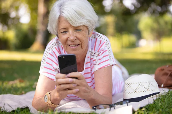 Mulher Idosa Deitada Parque Olhando Para Smartphone — Fotografia de Stock