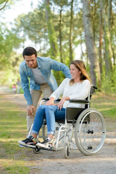 与男朋友坐在轮椅上的年轻女子 — 图库照片