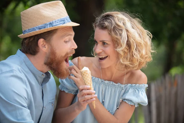 公园里的一对调情的情侣共享着一个冰激凌 — 图库照片
