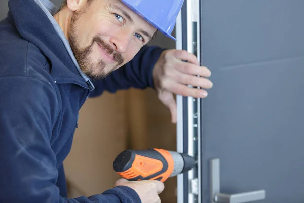 Glückliche Männliche Arbeiter Bohrt Ein Loch Eine Tür — Stockfoto