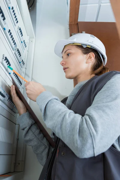 Female Electrician Checking Distribution Fuseboard — ストック写真
