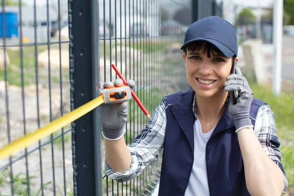 Eine Lächelnde Arbeiterin Die Zaun Misst Und Telefon Benutzt — Stockfoto