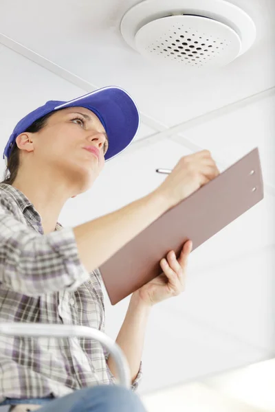 Vrouw Schrijven Klembord Terwijl Tanding Een Ladder — Stockfoto