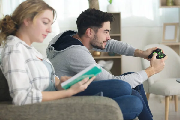 Man Playing Video Games While Women Reads Book Home — Stock Photo, Image