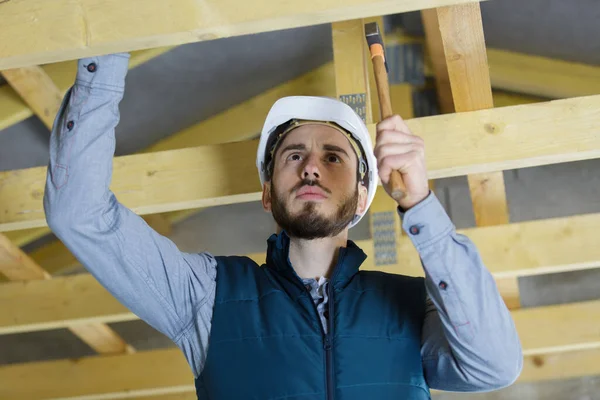 屋梁上有锤头的年轻建筑工人 — 图库照片