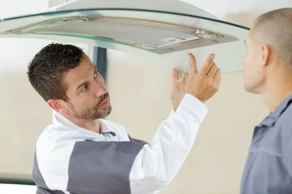 Two Workmen Installing Domed Glass Extractor Hood — 스톡 사진