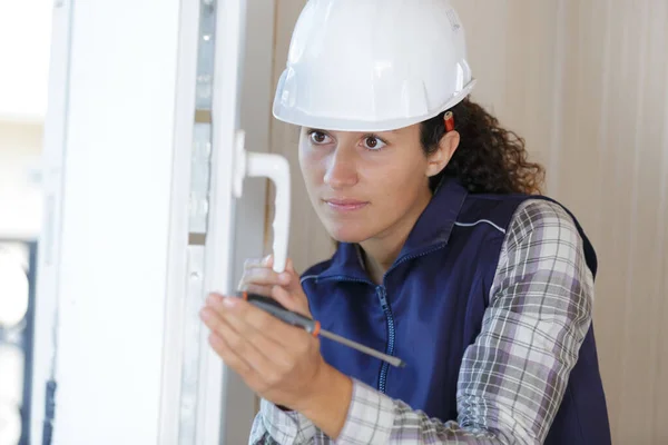 Kobieta Budowniczy Działa Pomocą Śrubokrętu Naprawić Drzwi — Zdjęcie stockowe