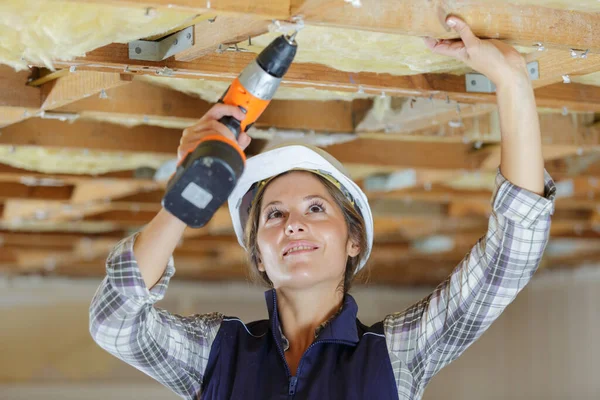 Female Construction Worker Using Cordless Drill Wooden Ceiling Joists — стоковое фото