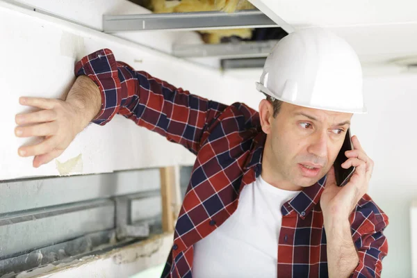 Senior Builder Wearing Helmet Receives Phonecall While Working — 스톡 사진