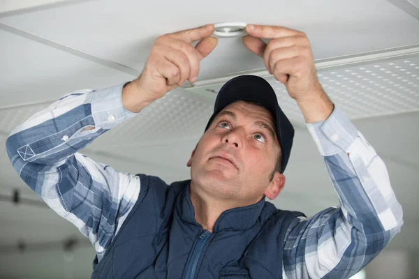 天井の光を修理する電気技師 — ストック写真