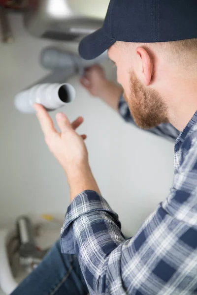 Mladý Muž Opravuje Kapající Trubku Pod Dřezem — Stock fotografie