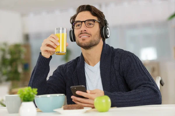 Man Eating Breakfast Using Smartphone Wearing Headphones — Stockfoto