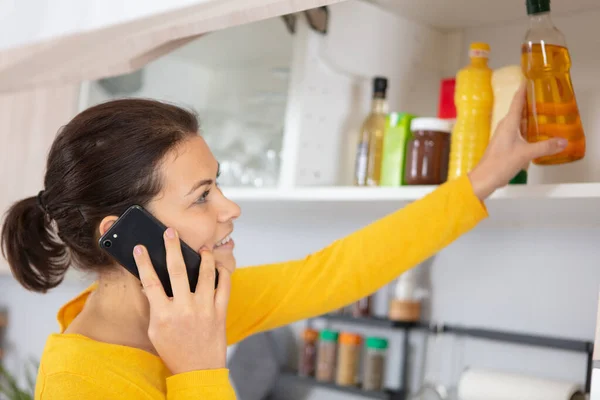 Νεαρή Γυναίκα Που Χρησιμοποιεί Smartphonein Κουζίνα Της — Φωτογραφία Αρχείου