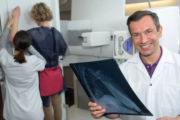 woman undergoing mammography scan assisted by male doctor