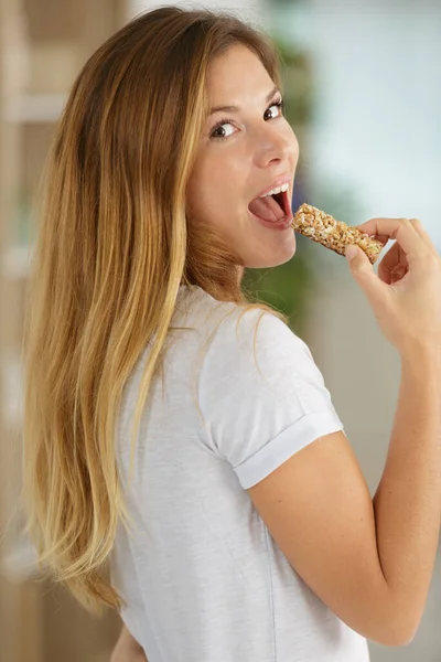 美しい若い女性がシリアルキャンディーバーを食べる — ストック写真