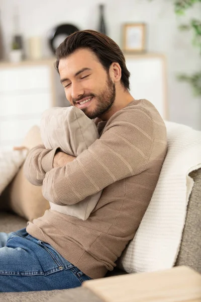 Όμορφος Χαρούμενος Νεαρός Άνδρας Κάθεται Στον Καναπέ Στο Σπίτι — Φωτογραφία Αρχείου