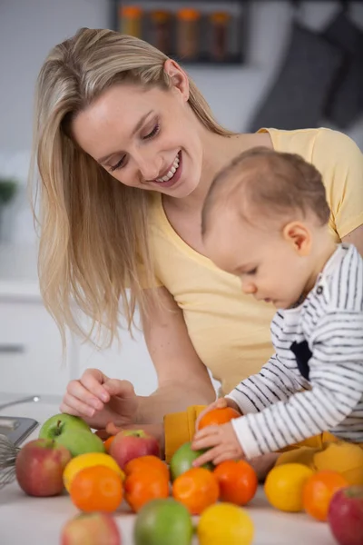 幸せな母親と赤ちゃんと果物をテーブルの上に置いて — ストック写真