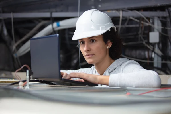 female contractor using laptop in roofspace