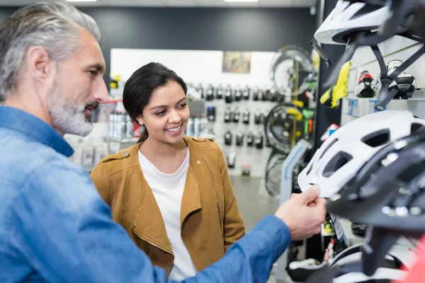 若い女性が自転車屋でヘルメットを選ぶ — ストック写真