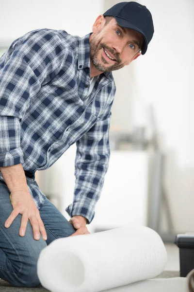 床断熱材のロールを展開する男 — ストック写真