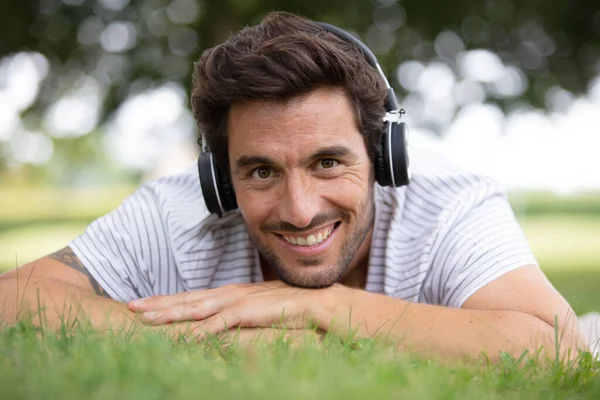 Młody Człowiek Relaksujący Się Zielonej Trawie Słuchawkami — Zdjęcie stockowe