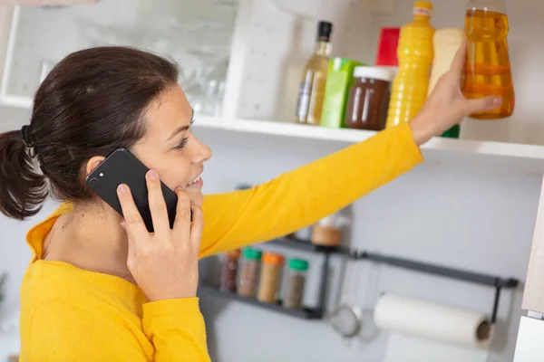 Mulher Que Toma Ingrediente Armário Falar Telefone — Fotografia de Stock